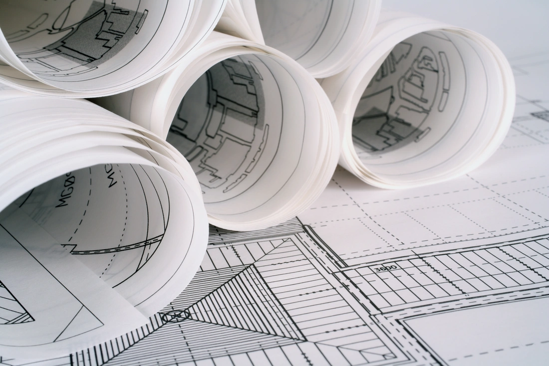 Rolled architectural drawings resting on a detailed building plan