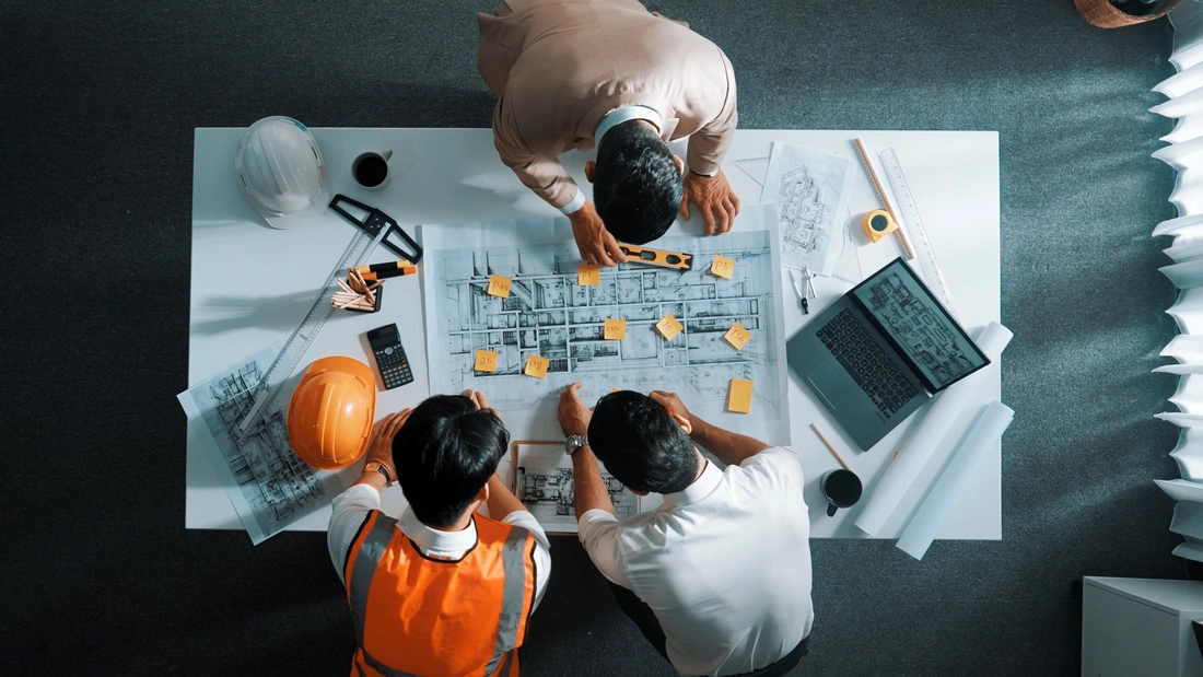 Overhead view of a team reviewing building plans around a table